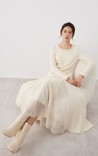 Beige long-sleeve top with crew neck and draped front; seated styling with sheer tulle skirt