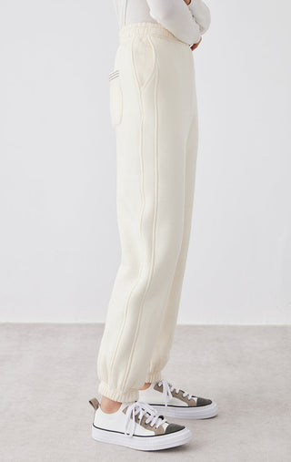 Cream White relaxed-fit pants, side view with vertical seam detailing and tapered legs