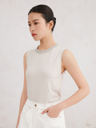 White sleeveless tank top with beaded neckline, worn with light pants