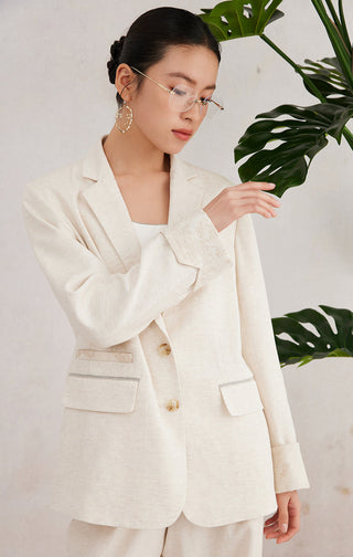 Beige tailored blazer detail: flap pockets and gold button front