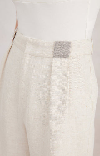 Close-up of white shorts waistband with beaded square trim and button detail