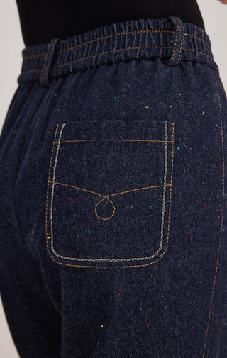 Denim blue trousers close-up: elastic waistband and square front patch pocket with stitching