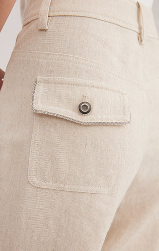 Beige utility-style pocket with stitched flap and metal grommet on cotton-linen pants