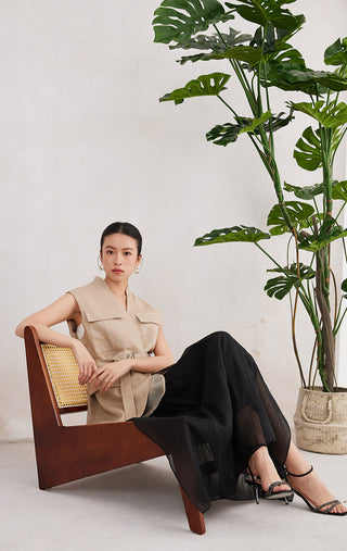 Camel linen sleeveless belted vest layered with black skirt; utility pockets and belt