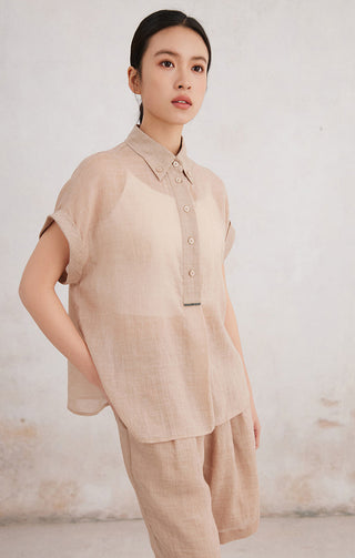 Apricot short-sleeve button-up shirt with front buttons and chest placket detail.