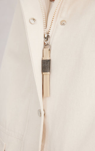 Beige jacket zipper close-up with shiny pull and fabric zipper guard