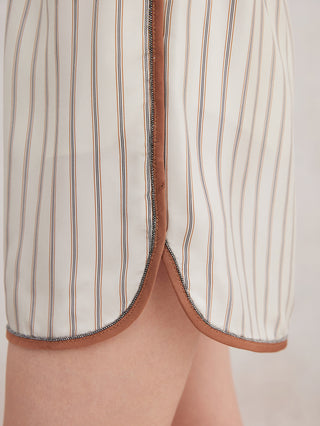 Close-up of beige striped silk shorts hem with contrast trim and side opening