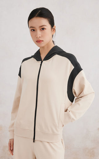 Apricot zip-up hoodie with black shoulder panel, front pockets, and drawstring hood