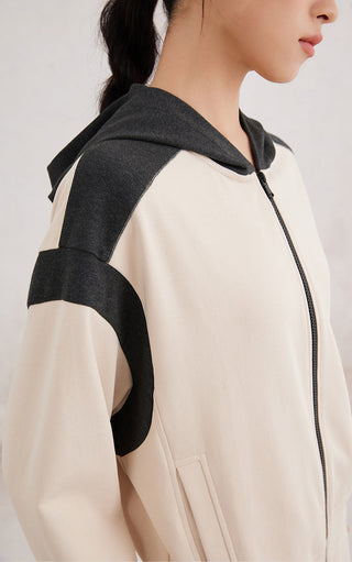 Close-up of apricot double-color zip-up hoodie: black hood, sleeve panel, zip front