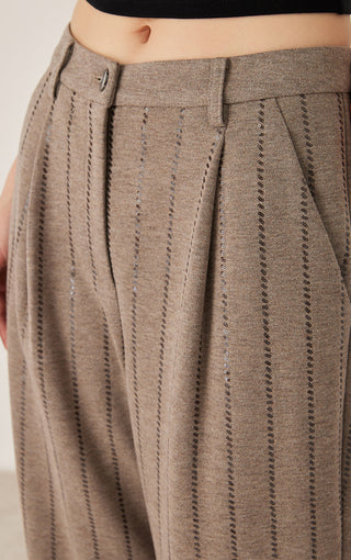Waistband close-up: dark camel pinstriped pants with sequin-embellished button detail
