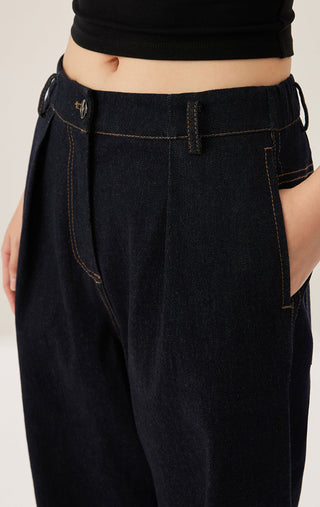 Close-up of black/dark wash wide-leg trousers: seams and front pleat detail.