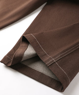 Bottom hem detail of brown wide-leg trousers with visible inner facing