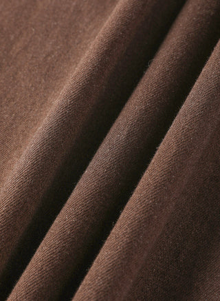 Close-up of brown fabric texture and stitching lines on wide-leg trousers