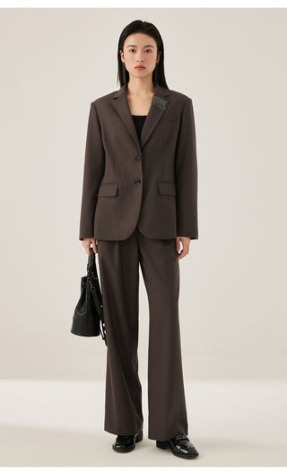 Model wearing dark brown wool-blend blazer with matching trousers and shimmer fringe detail