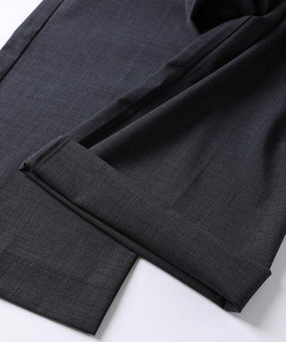 Black tailored pants hem and folded cuff detail over dark inner lining