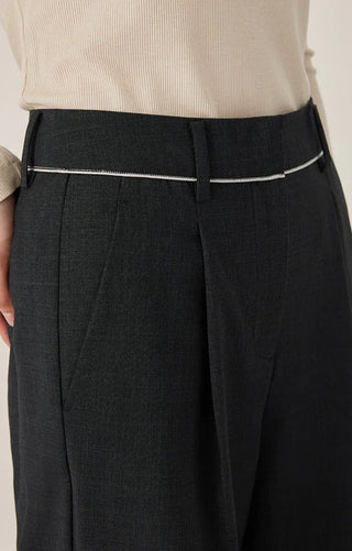 Black pants waistband detail with belt loops and contrast trim, front pleats visible