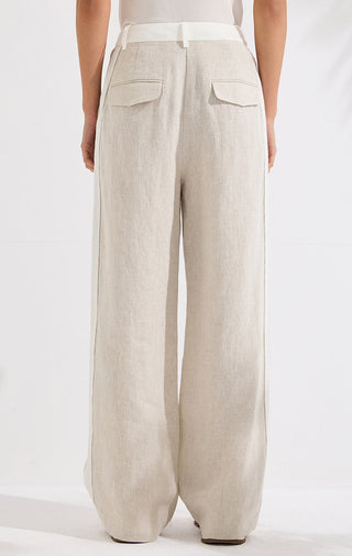 Beige linen wide-leg trousers from back view with flap pockets and relaxed legs