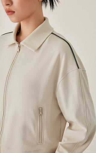 Oatmeal jacket close-up with stand collar, front zipper, and ribbed shoulder seam detail