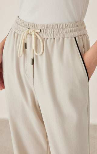 Close-up of cream waistband with elastic, drawstring cord, and side pocket opening