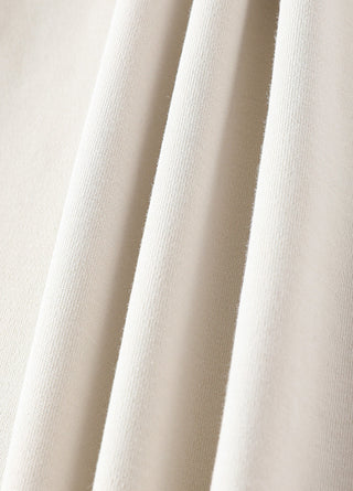 Close-up of cream wide-leg fabric with vertical seam lines and soft drape