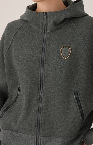 Close-up of dark gray zip hoodie: hood, front zipper, and beaded shield crest badge.