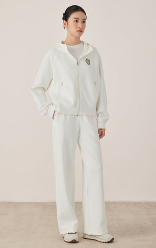 White cotton zip-up hoodie with hood and beaded shield crest badge; matching drawstring-less look.