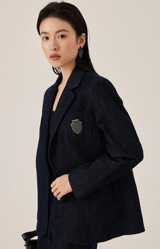 Dark blue tailored blazer with crest emblem, notched lapel, and side flap pockets