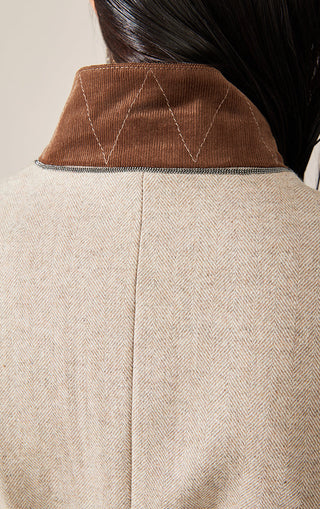 Back of beige vest with brown collar trim and stitched seam details