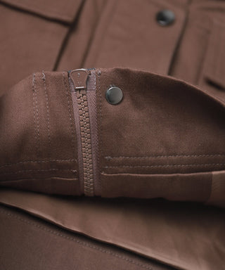 Brown jacket sleeve cuff detail with zipper seam and metal snap button