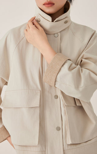 Beige stand-collar jacket close-up, button placket and contrast cuff details