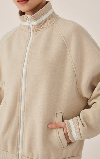 Khaki zip-up track jacket close-up of white zipper and kangaroo pocket panel