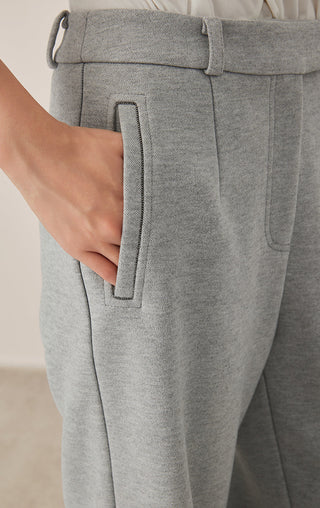 Gray-blue pants close-up: stitched front pocket flap and pleated waistband area.