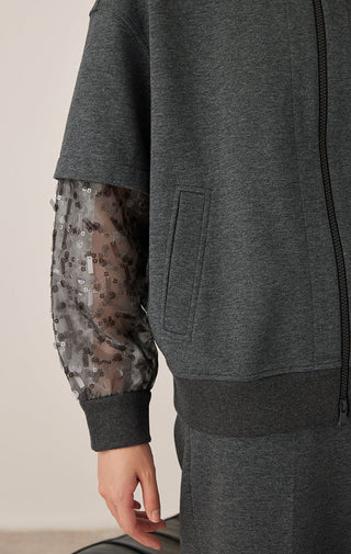 Dark gray zip hooded jacket detail: kangaroo pocket and sheer patterned mesh sleeve