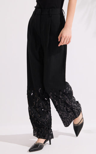 Lower front view: black pinstripe wide-leg trousers with sequined draped hem panels