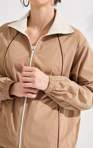 Close-up: khaki zip track jacket with off-white collar, zipper pull, and dark red piping