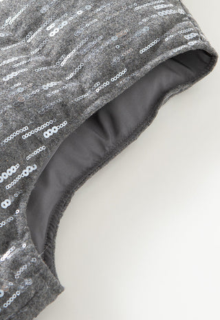 Grey sequin vest fabric edge with dark inner lining, curved seam, and quilted panel