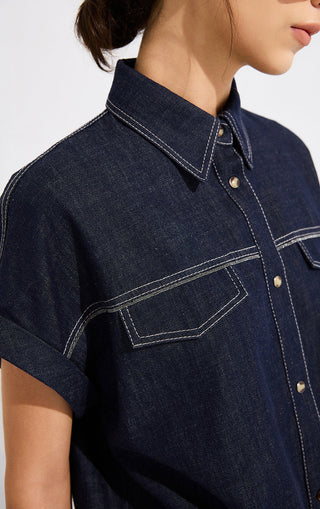 Ink blue denim cropped shirt close-up: contrast yoke seam, button placket, chest pocket