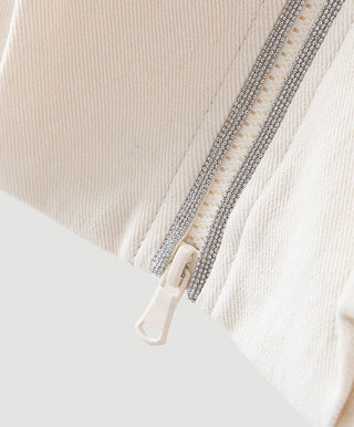 Beige zip-up jacket close-up: rhinestone-trimmed zipper on the front.