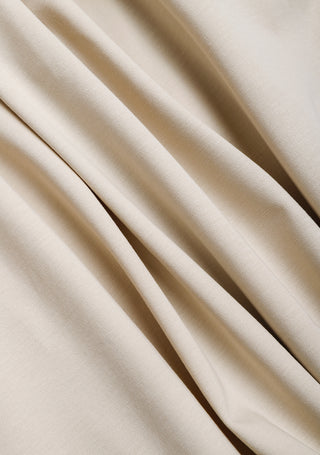 Close-up of camel pleated skirt fabric with fine vertical pleats.