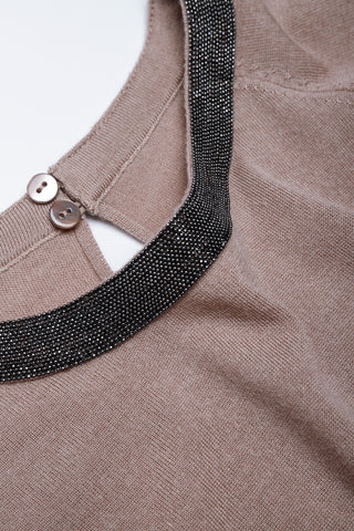 Close-up of dark beaded neckline trim with small button detail on taupe knit dress