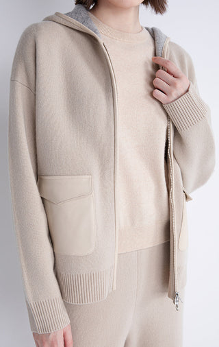 Beige hooded jacket close-up with patch pockets, zip front, and ribbed hem cuffs