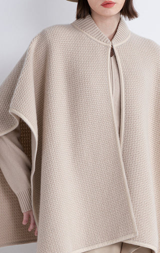 Beige cape close-up: zip front, textured knit, and shearling-trim edge