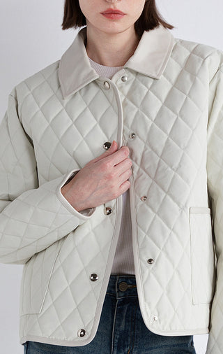 White quilted down jacket close-up: stand collar, snap buttons, chest pocket.