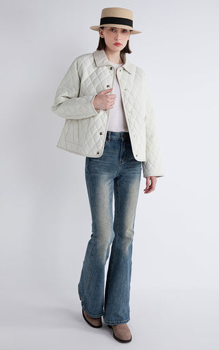 White quilted down jacket worn with blue jeans, button front and diamond quilting.
